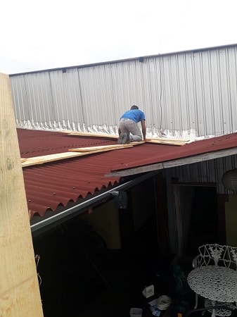 homem impermeabilizando parede sobre o telhado