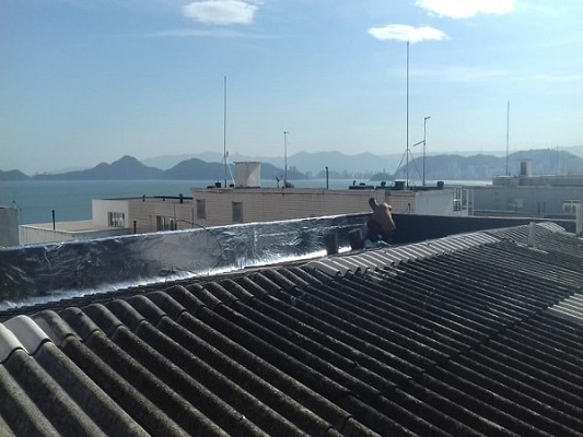 homem impermeabilizando parede sobre o telhado